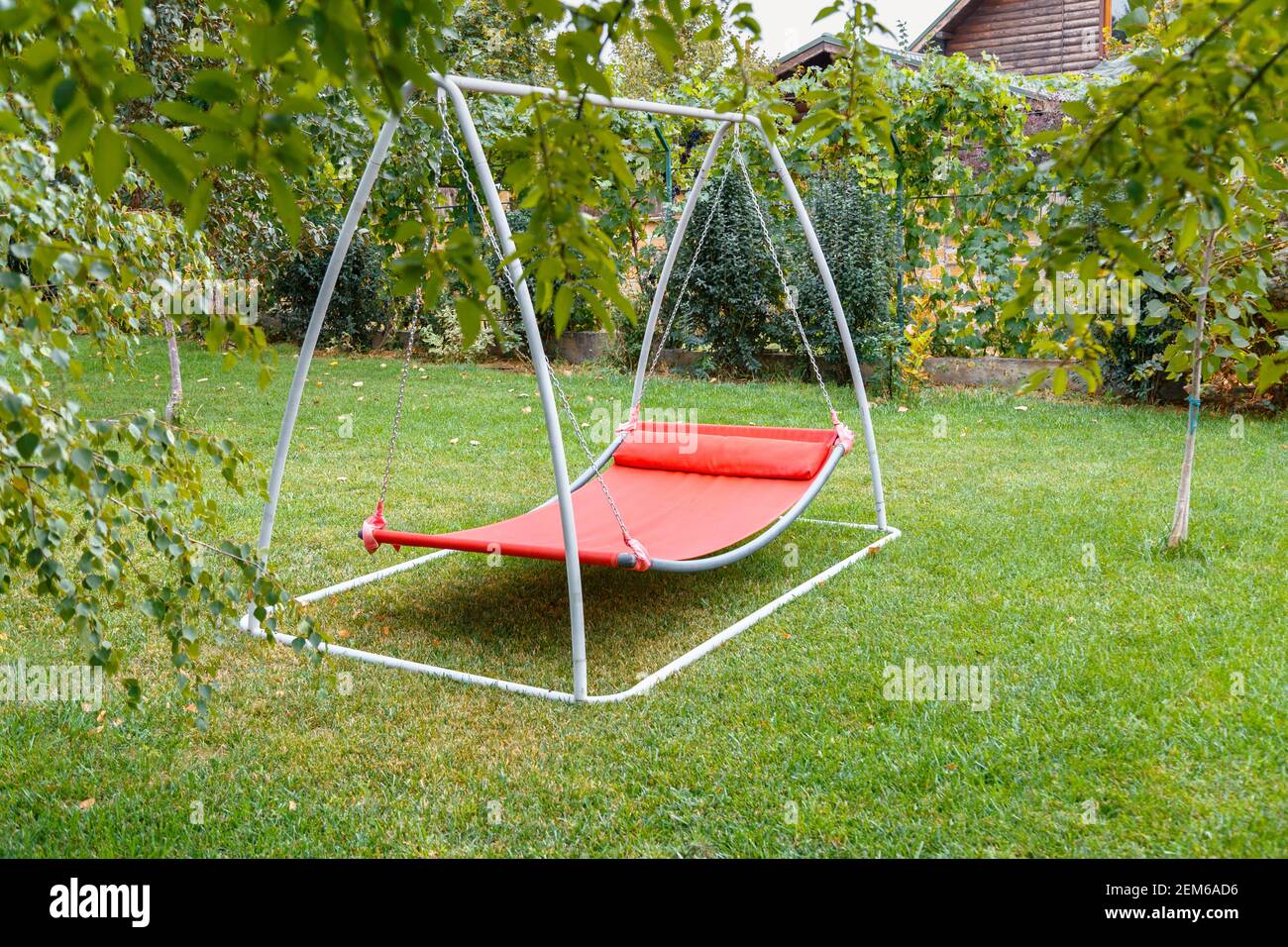 Hammock swing in metal frame with nobody on green lawn in backyard near  house cottage. Rest relax relaxation alone on Red hammock swing in Summer  Stock Photo - Alamy