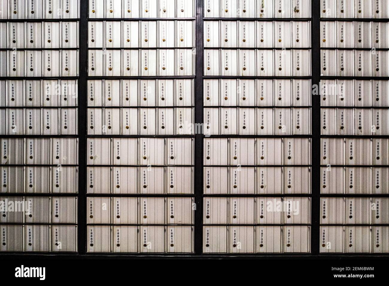 Post office boxes on a wall create a grid of lines at a branch of the United States Postal Service. Stock Photo