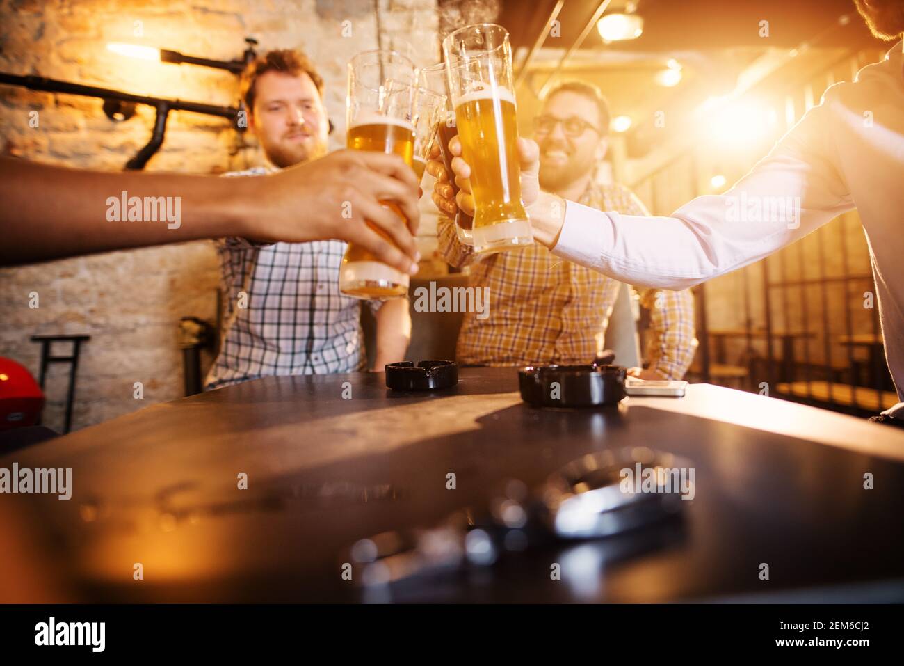Close up focus view of glasses with draft beer while male friends