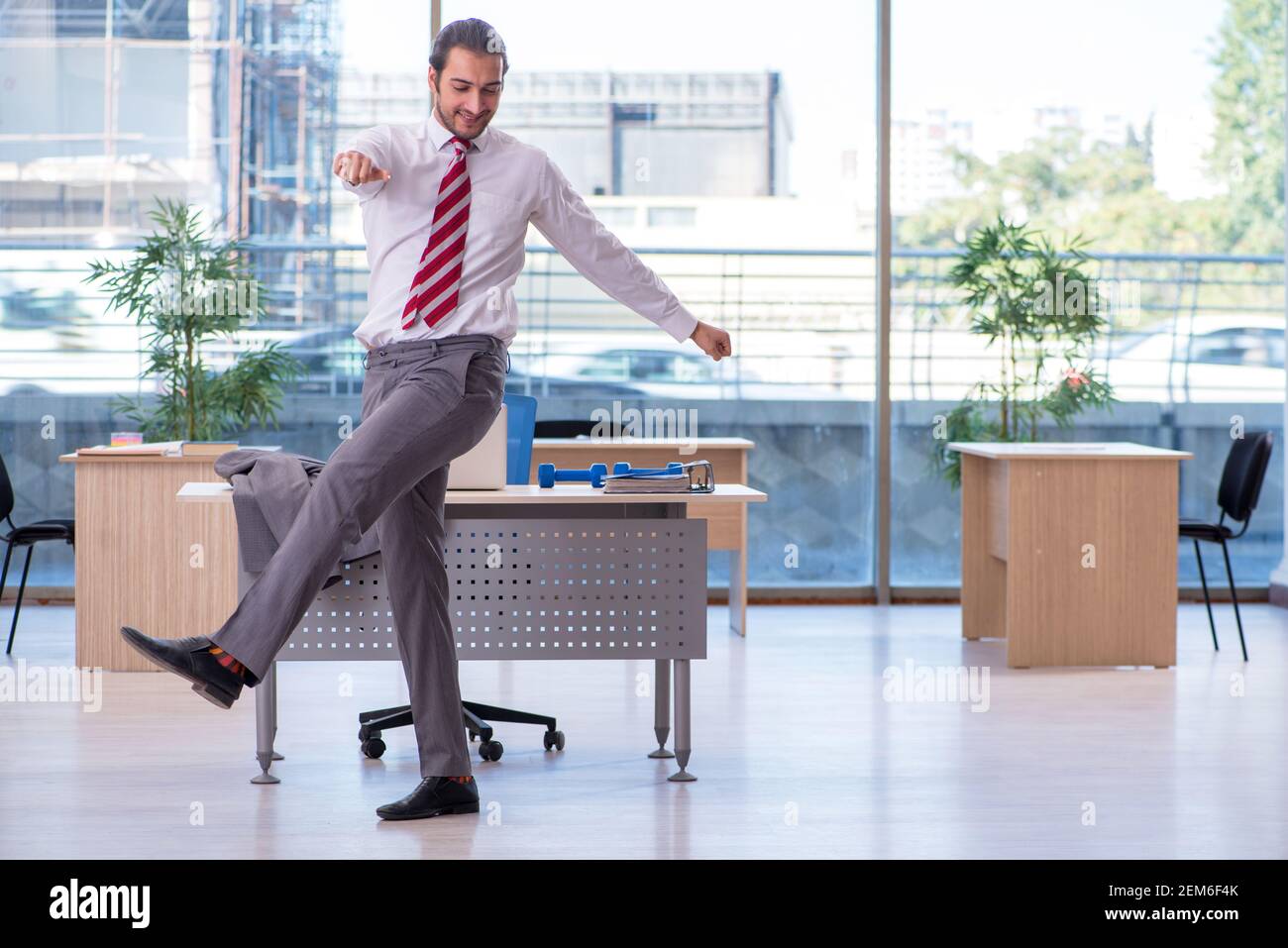 Young employee doing sport exercises at workplace Stock Photo - Alamy