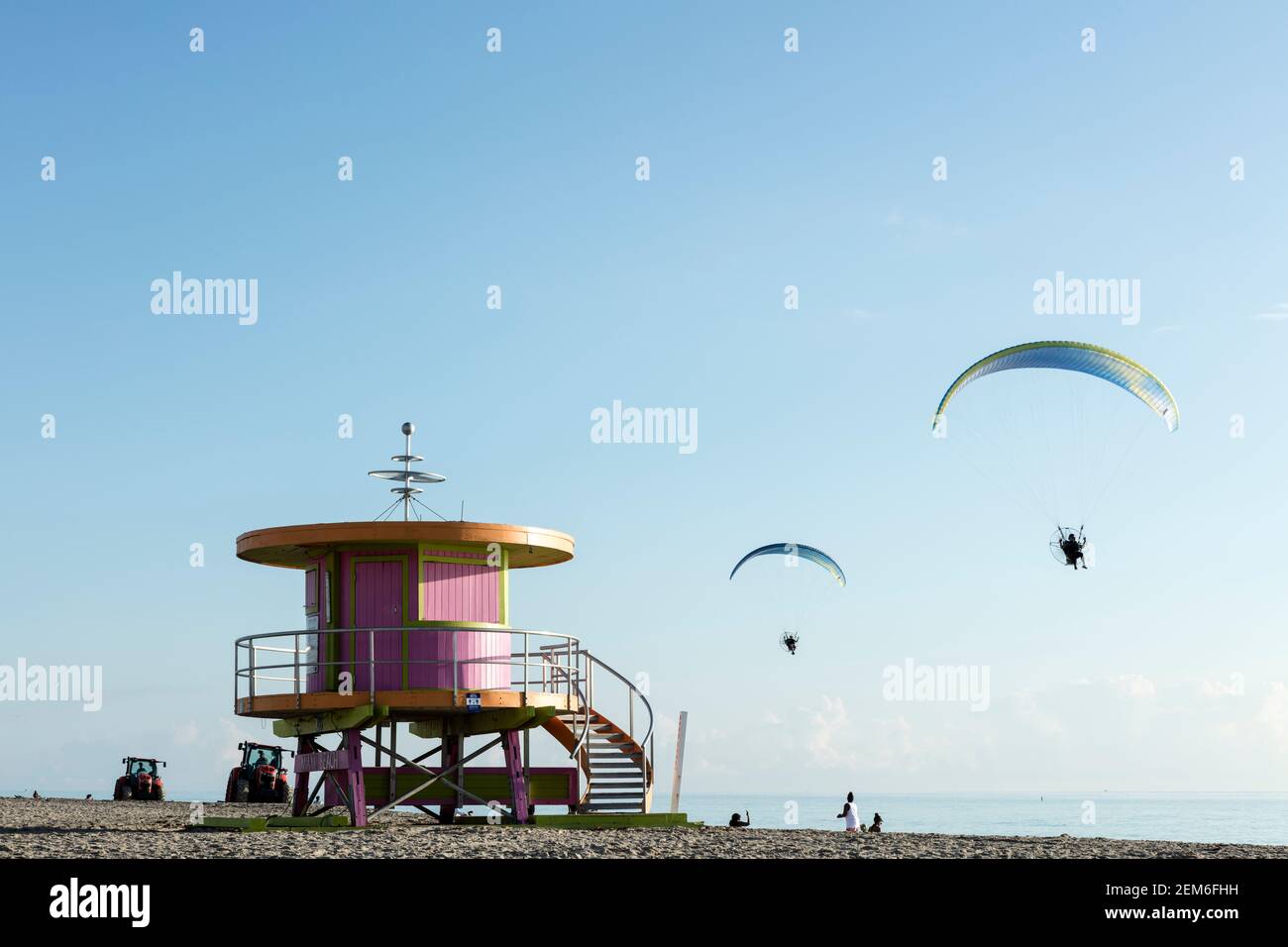 Two powered paraglider fly over one of the iconic lifeguard towers on