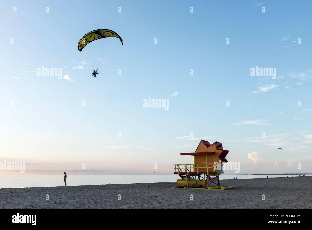 A powered paraglider flies over one of the iconic lifeguard towers on