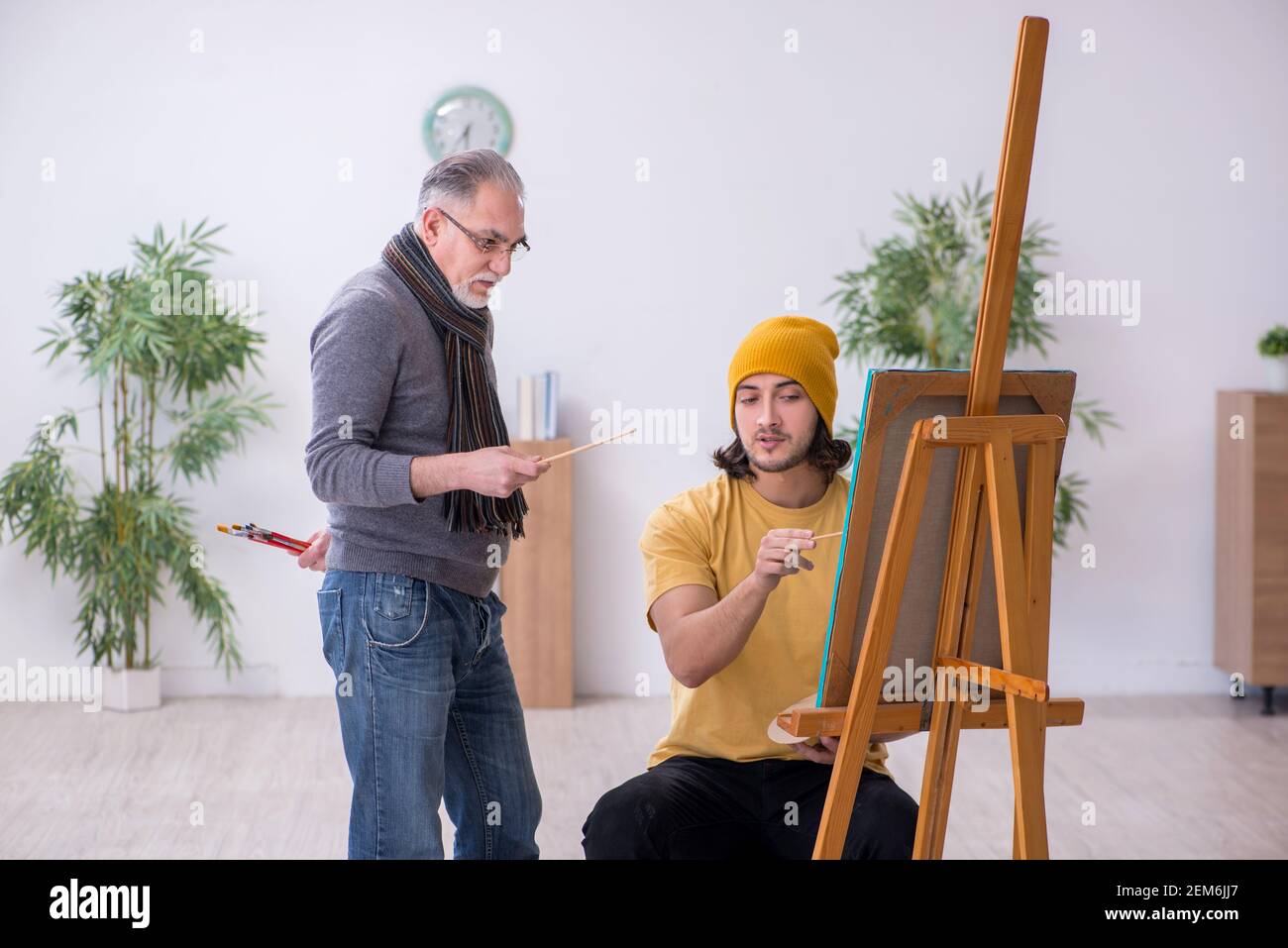 Young man taking lesson from experienced painter Stock Photo