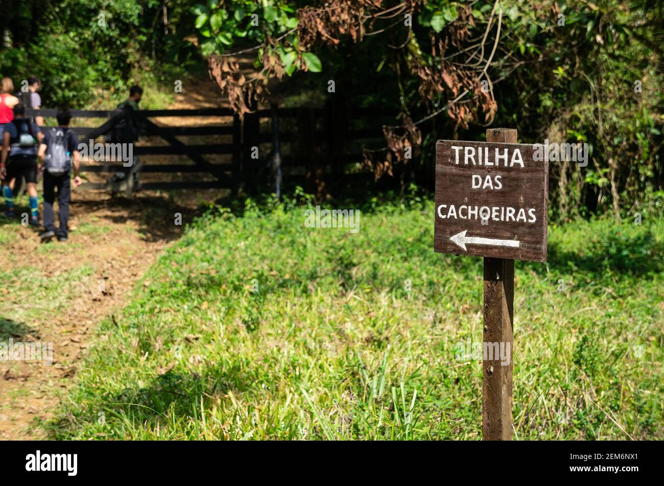 A wooden signboard pointing the direction to Trilha das Cachoeiras (Waterfalls hiking trail) path in Serra do Mar estate park, Cunha nucleus. Stock Photo