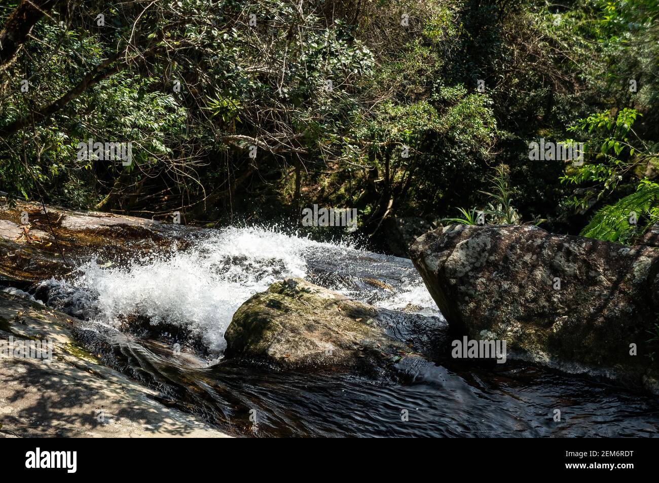 Fresh crystal clear water current from Ipiranguinha waterfall around over rock formations. This is one of Serra do Mar forest tourist attractions. Stock Photo