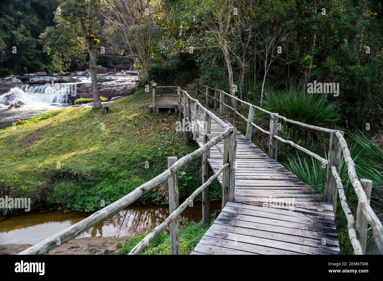 The wood bridge at the beginning of Paraibuna river hiking trail with a waterfall in far back. This is a 1700m self guided trail in Cunha. Stock Photo