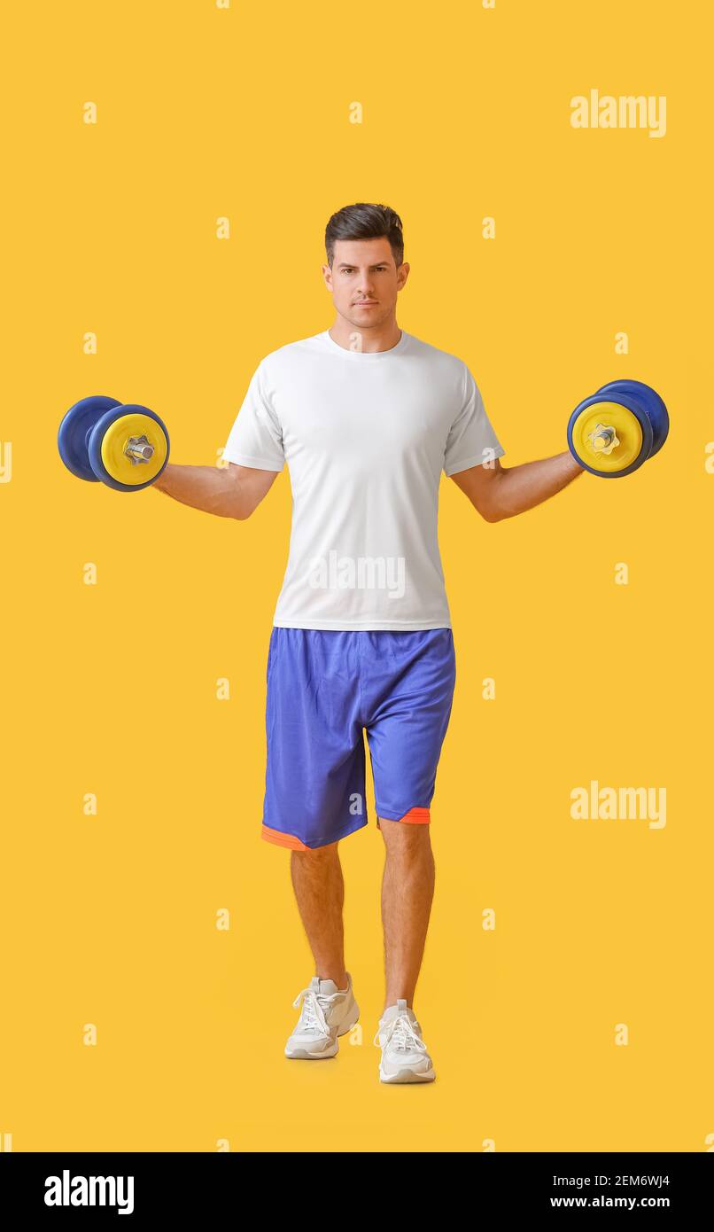 Sporty young man training with dumbbells on color background Stock Photo