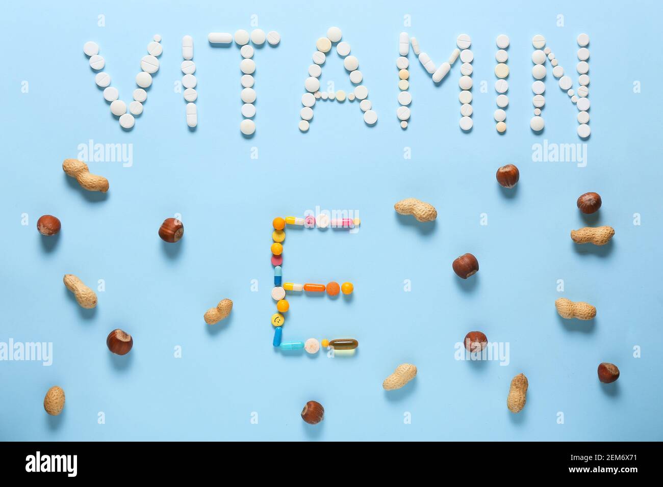 Text VITAMIN E made of pills with healthy nuts on color background Stock Photo