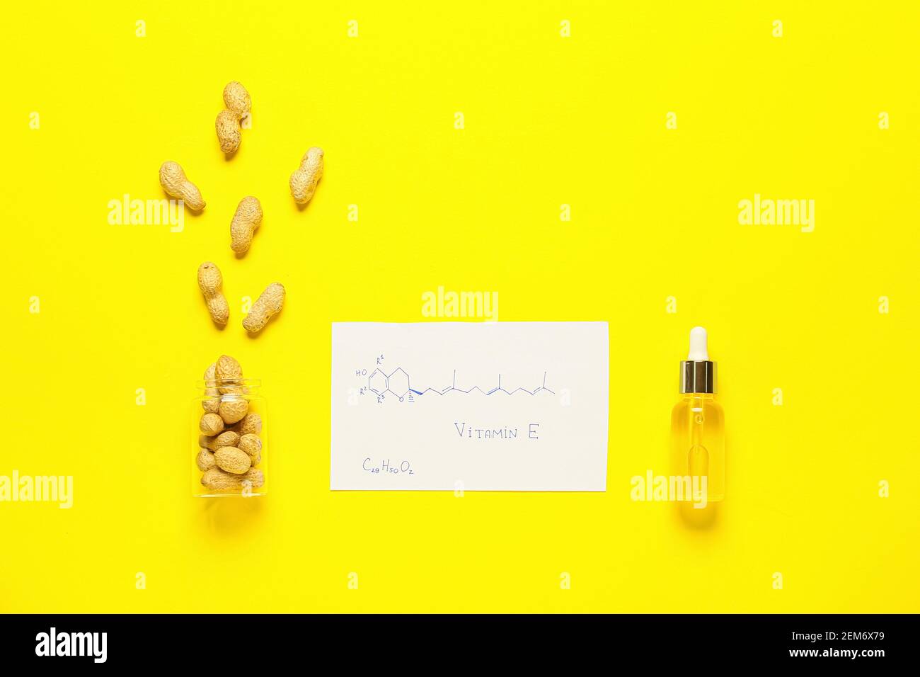 Structural formula of vitamin E and peanut nuts with oil on color background Stock Photo