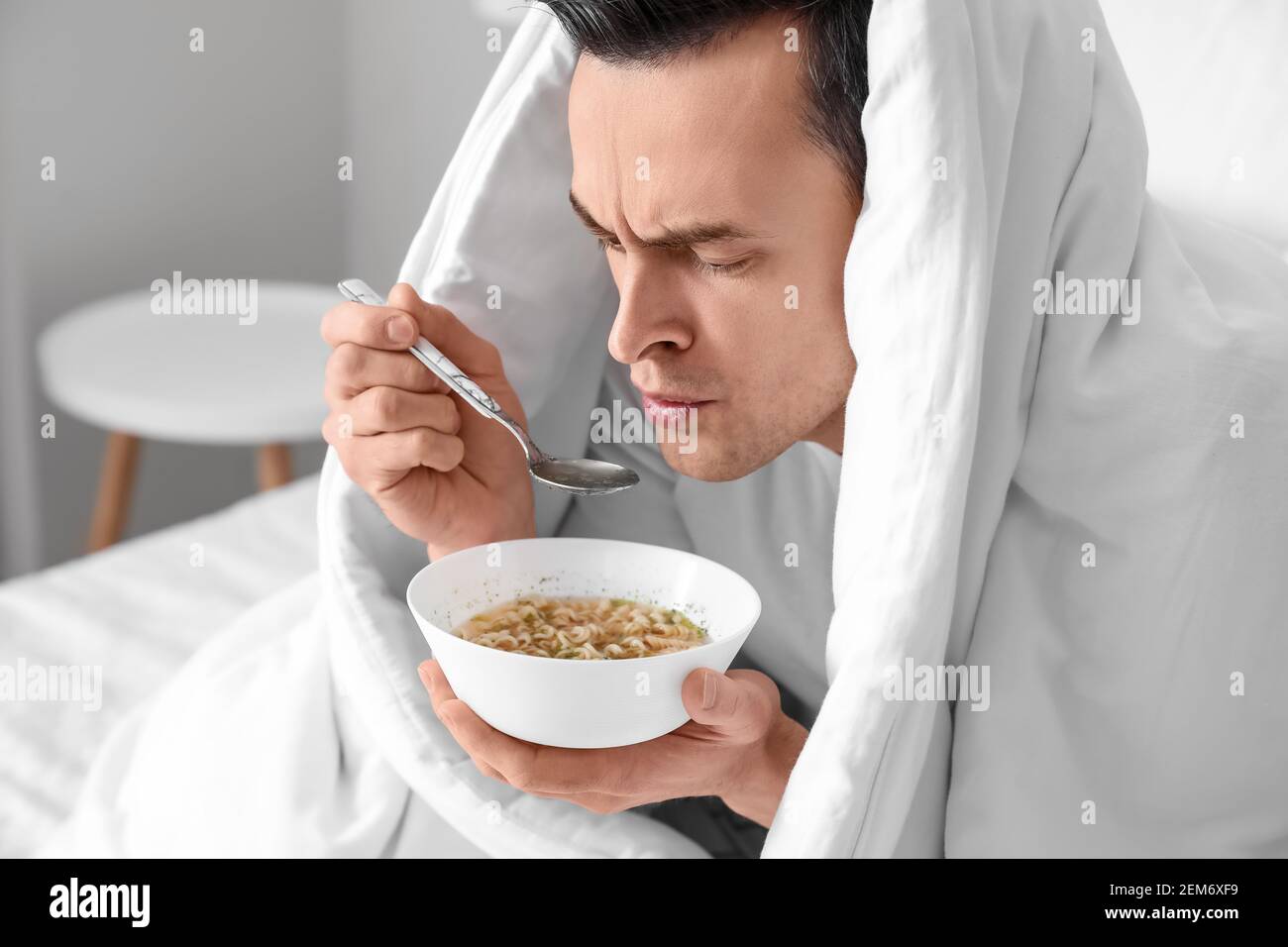 Sick man eating chicken soup at home Stock Photo Alamy