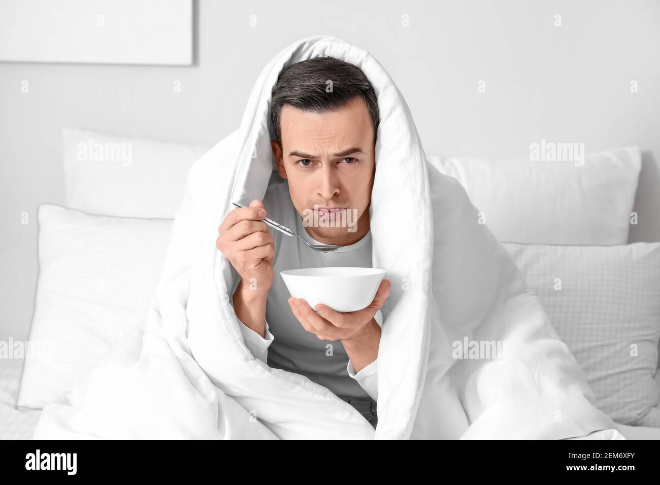 Sick man eating chicken soup at home Stock Photo Alamy
