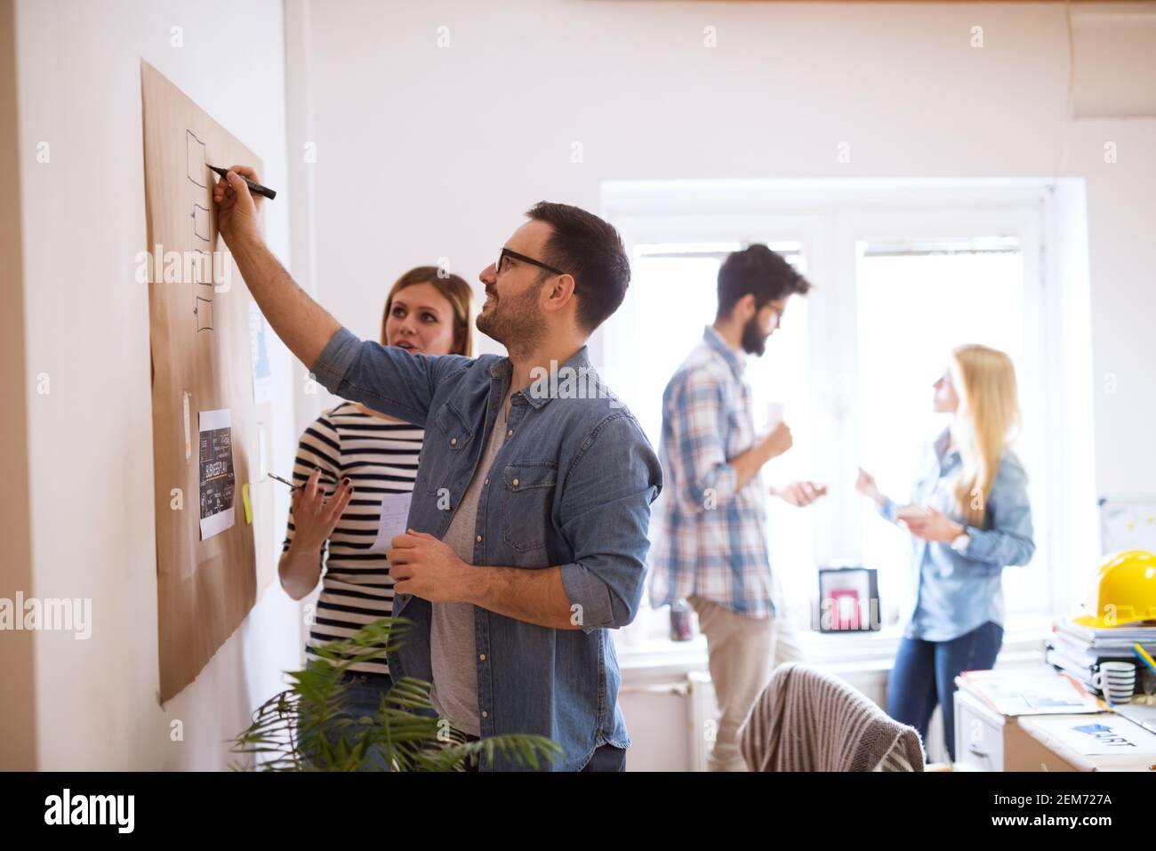 Young developers are brainstorming new algorithms how to make their software better optimized for users , while writing them down on a brownboard. Stock Photo