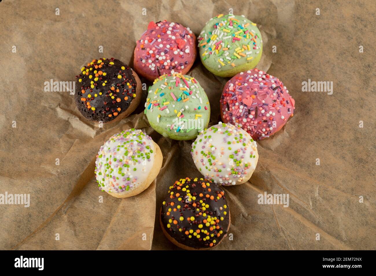 Sweet small doughnuts with sprinkles on a parchment paper Stock Photo