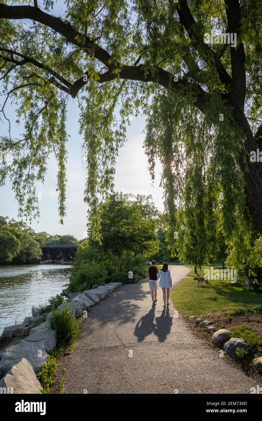 Couple hand in hand walking on a park trail along a river. Stock Photo