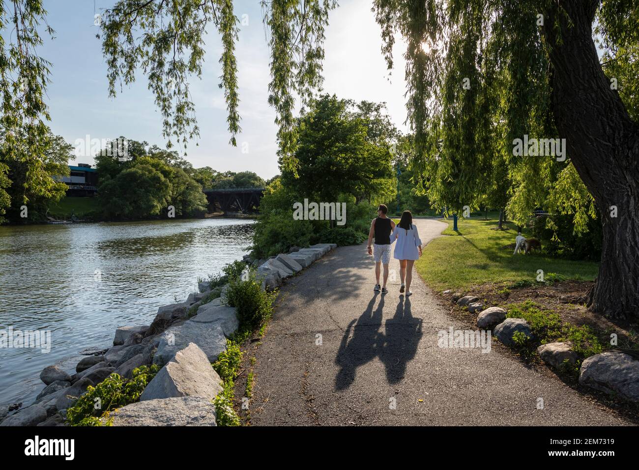 Couple hand in hand walking on a park trail along a river. Stock Photo