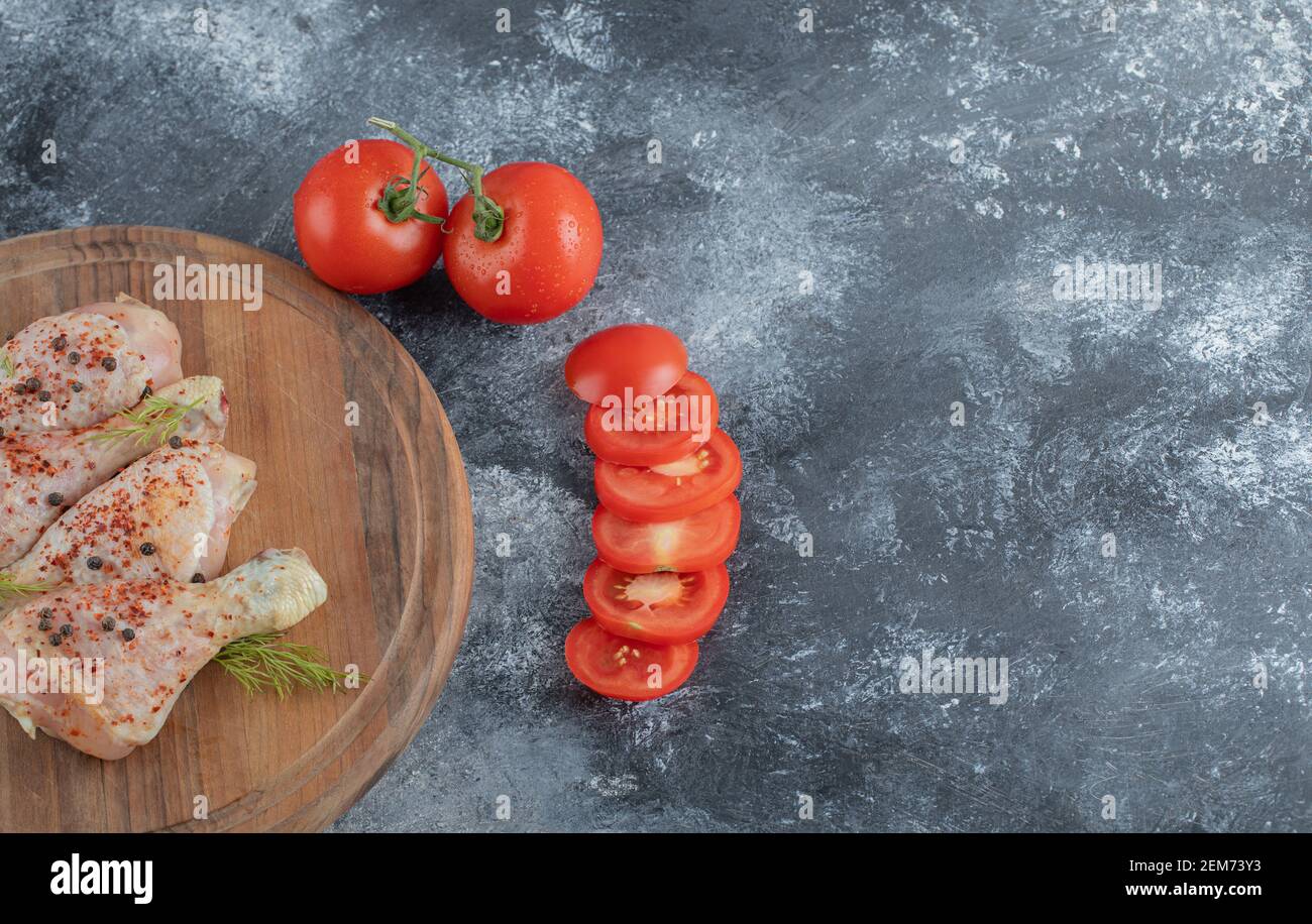 https://c8.alamy.com/comp/2EM73Y3/raw-chicken-legs-with-spices-and-sliced-or-whole-tomatoes-on-a-wooden-board-2EM73Y3.jpg