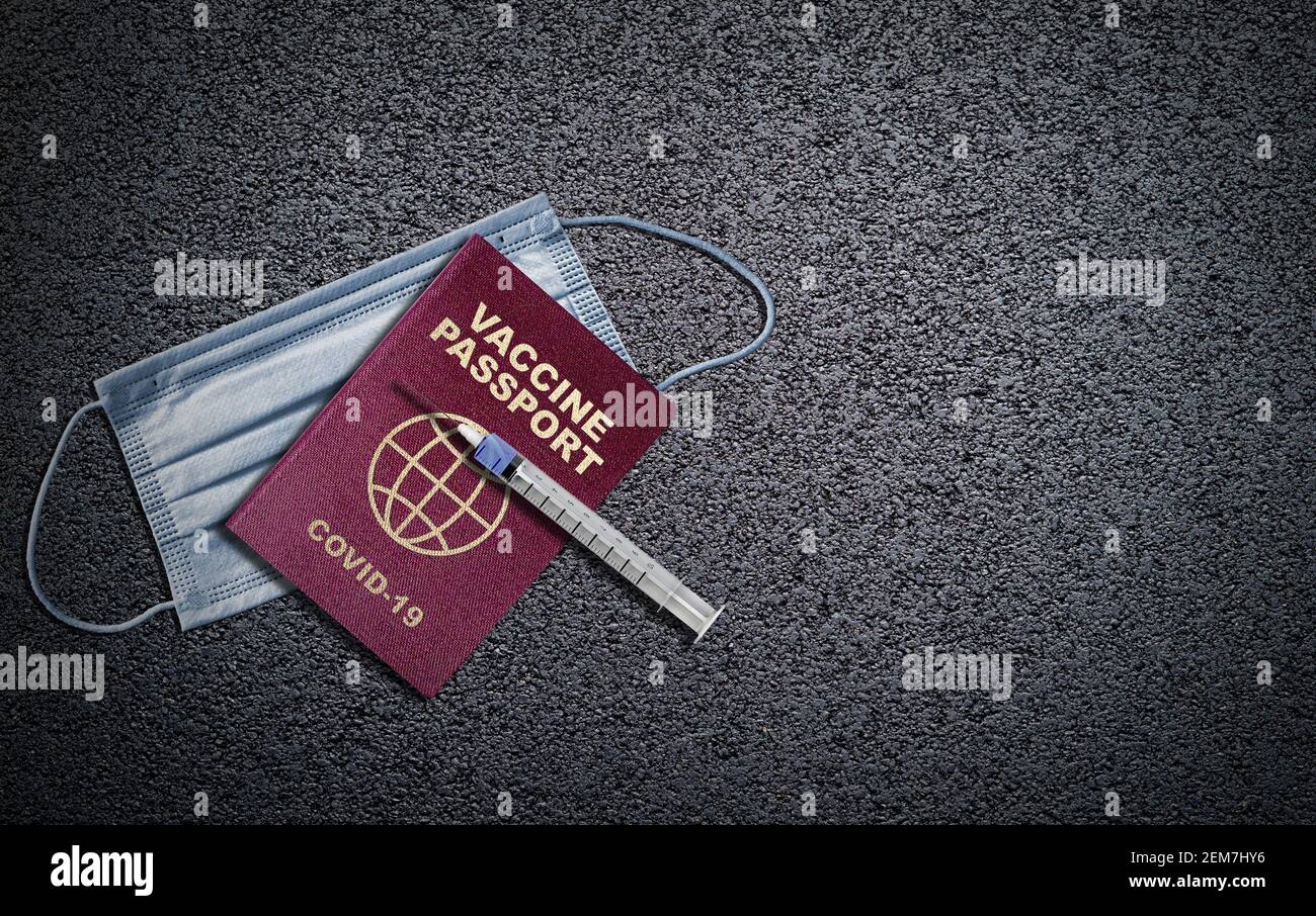 COVID-19 vaccine passport concept with syringe needle on passport and face mask on asphalt background with copy space. Concept of new normal travel an Stock Photo