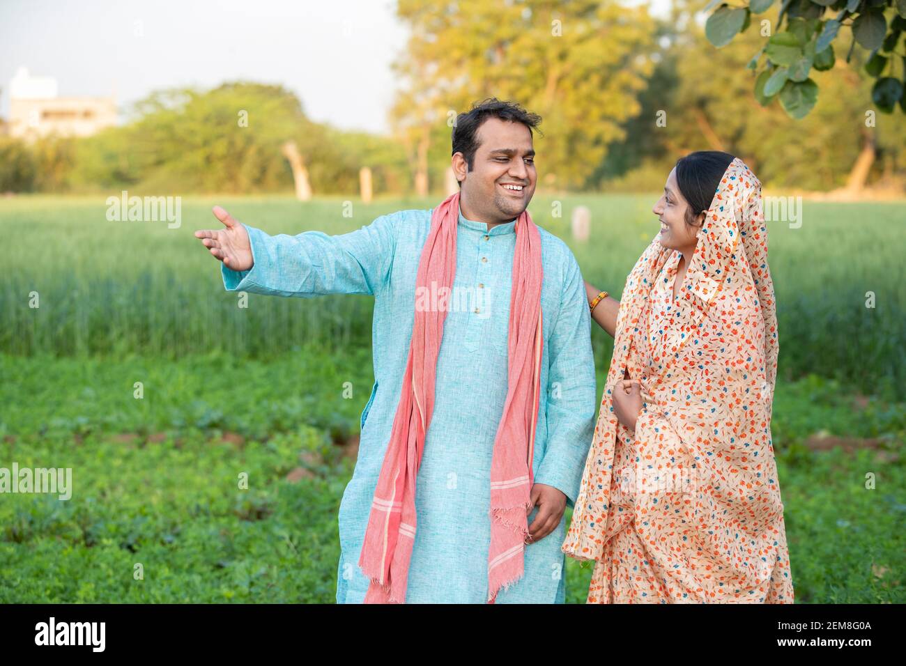 Happy young indian rural farmer couple in agricultural field looking at ...