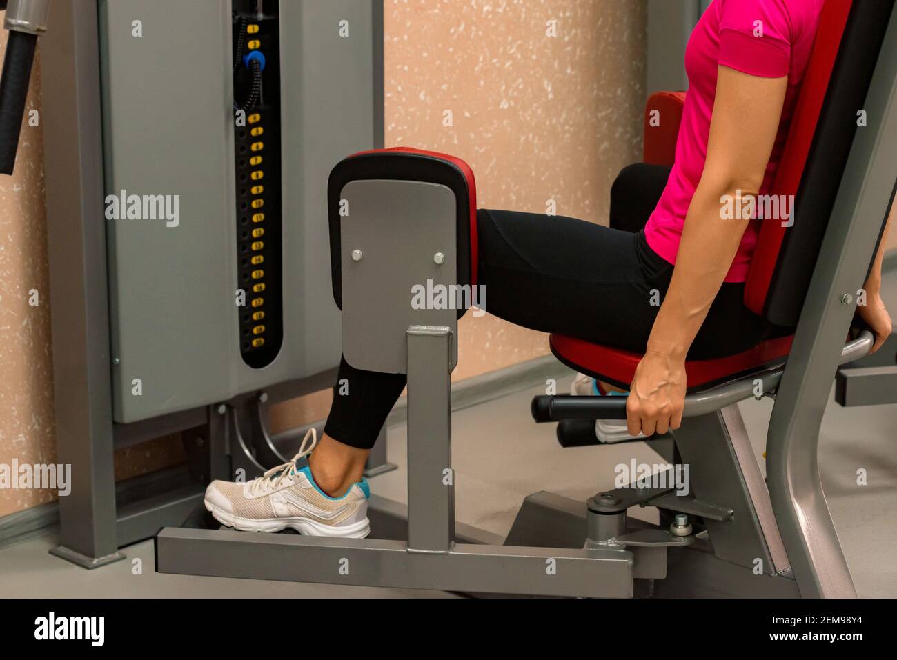 Side view slim woman doing leg exercises on gym machine. Selective focus  Stock Photo - Alamy