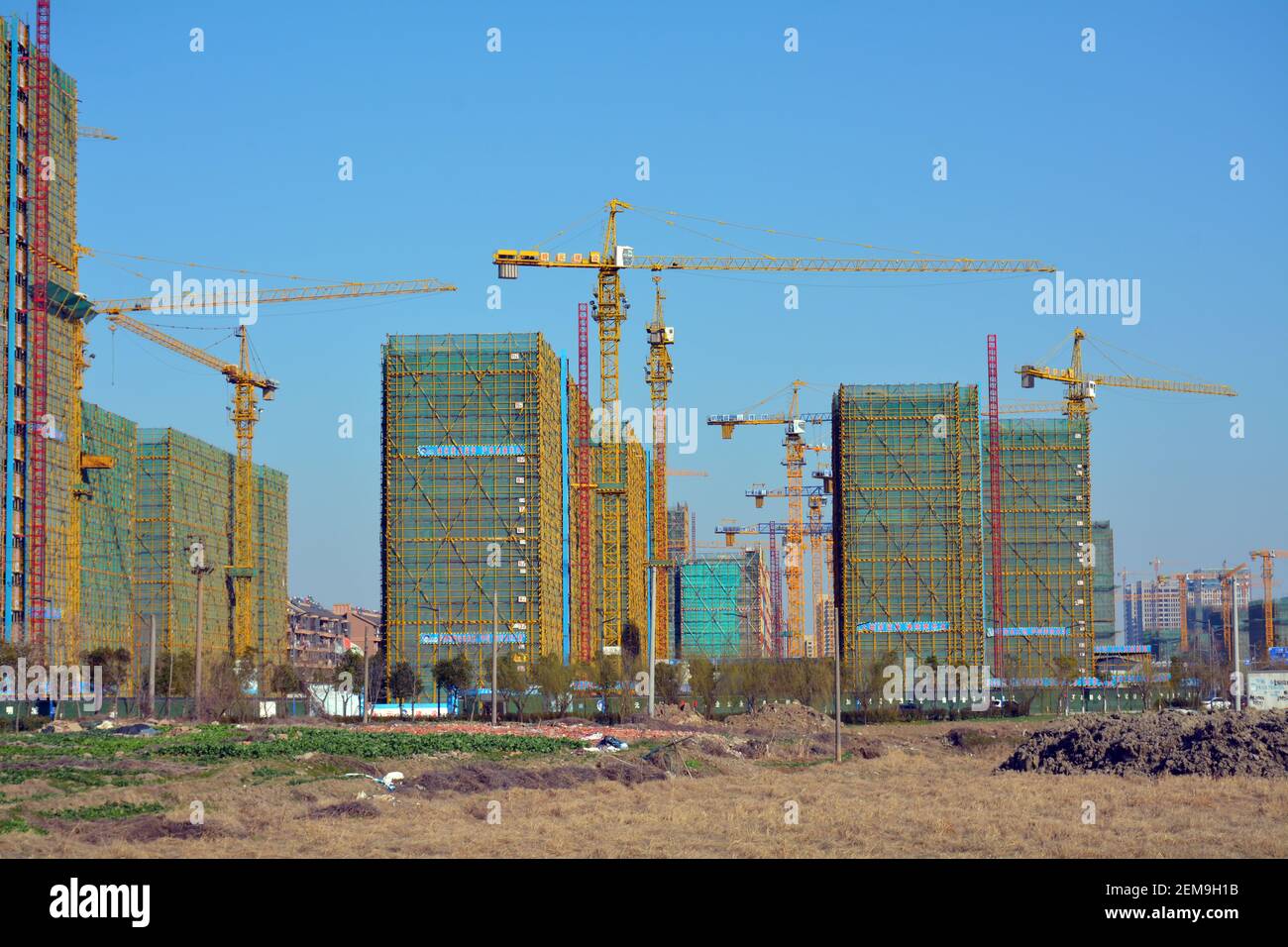 Tall yellow cranes and scaffolding on a Chinese city building site. New apartment blocks being built in Jiaxing,Zhejiang. Stock Photo