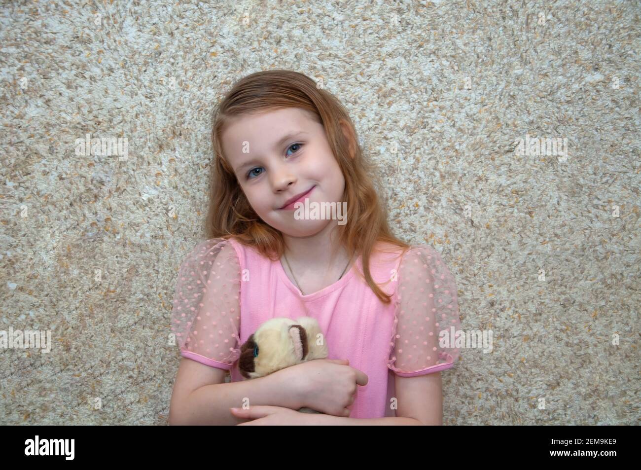 Girl with a soft toy rejoices and laughs. Stock Photo