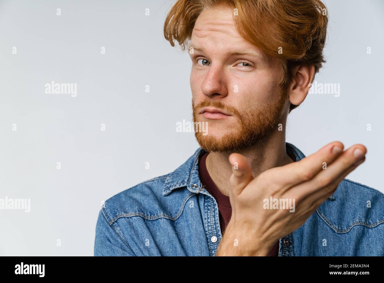 Confused handsome guy posing and holding copyspace isolated over white ...