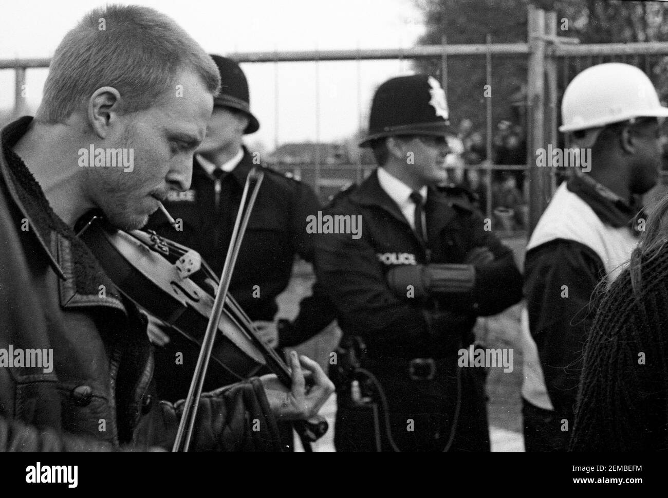 Fiddle players watched by Metropolitan Police officers at an anti roads protest in Wanstead, East London as part of the No M11 Link Road Campaign of direct action against the M11 Link Road road construction in 1994 Stock Photo