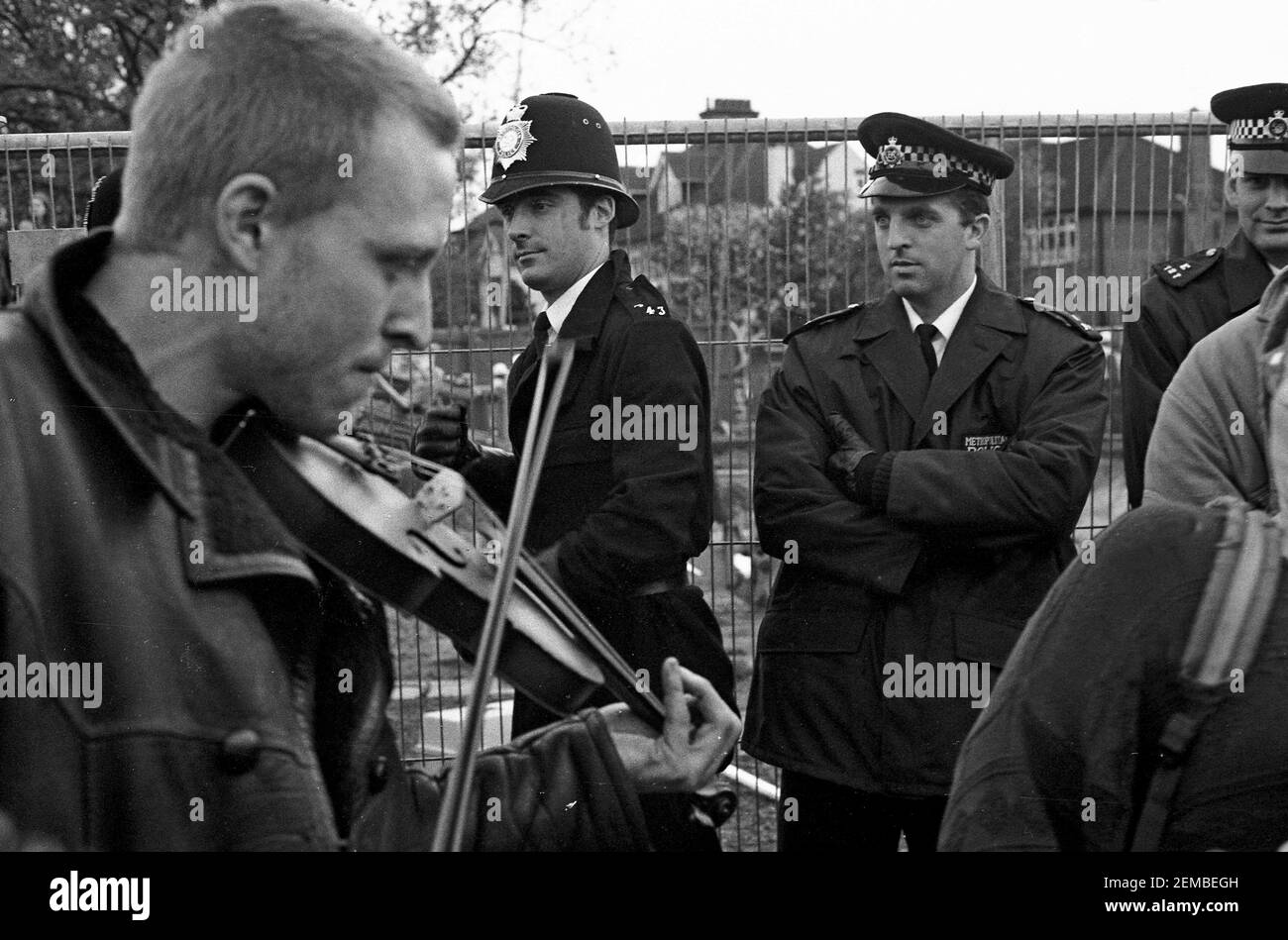 Fiddle players watched by Metropolitan Police officers at an anti roads protest in Wanstead, East London as part of the No M11 Link Road Campaign of direct action against the M11 Link Road road construction in 1994 Stock Photo