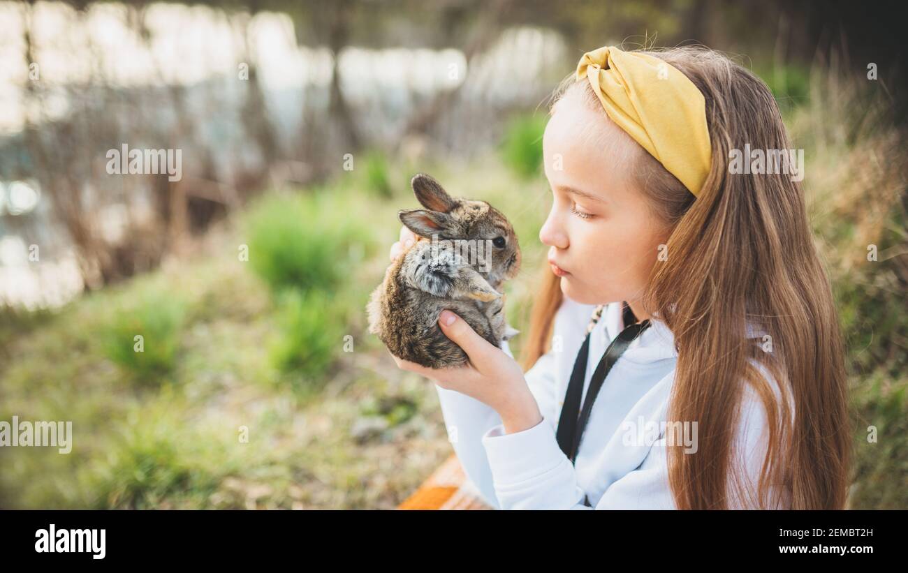 Happy little girl holding a cute fluffy rabbit. Friendship with the ...
