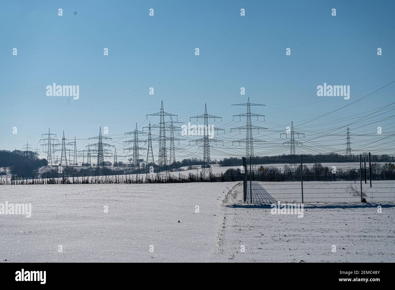Electricity pole made of natural material in a winter landscape with a clear blue sky Stock Photo