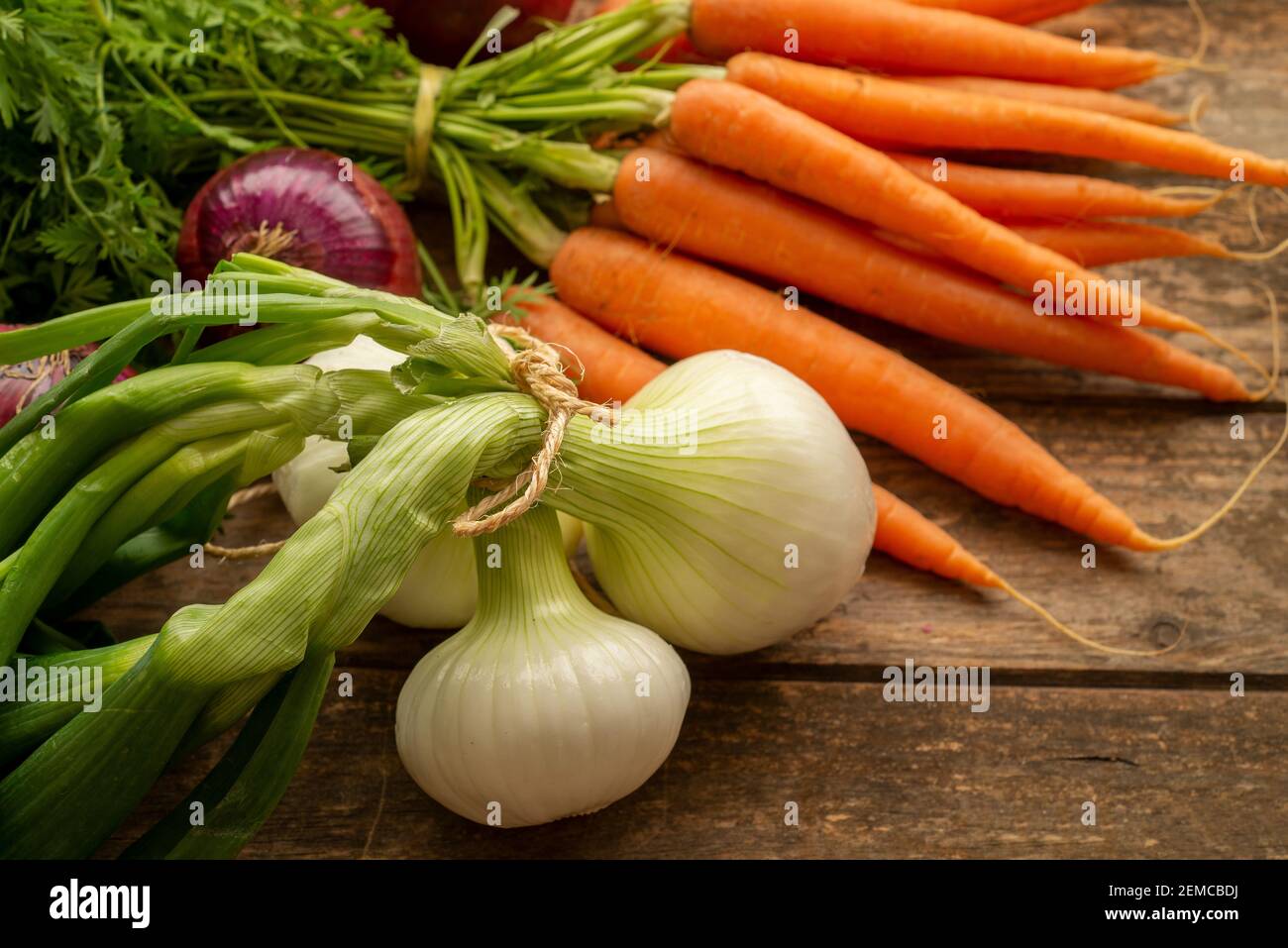 Fresh carrots bunch on rustic wooden background. Red onions on rustic wood. Different onions on wood. White onion on wood. Stock Photo