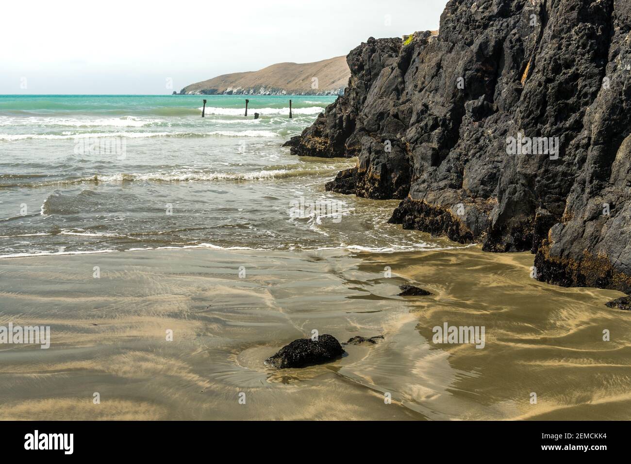Seawater gently beating against the rocky coastline at Okains Bay, Banks Peninsula, South Island, New Zealand. Stock Photo