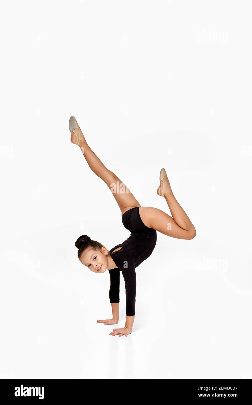 adorable little gymnast girl in black sportswear performs a handstand. child showing flexibility and acrobat balance Stock Photo