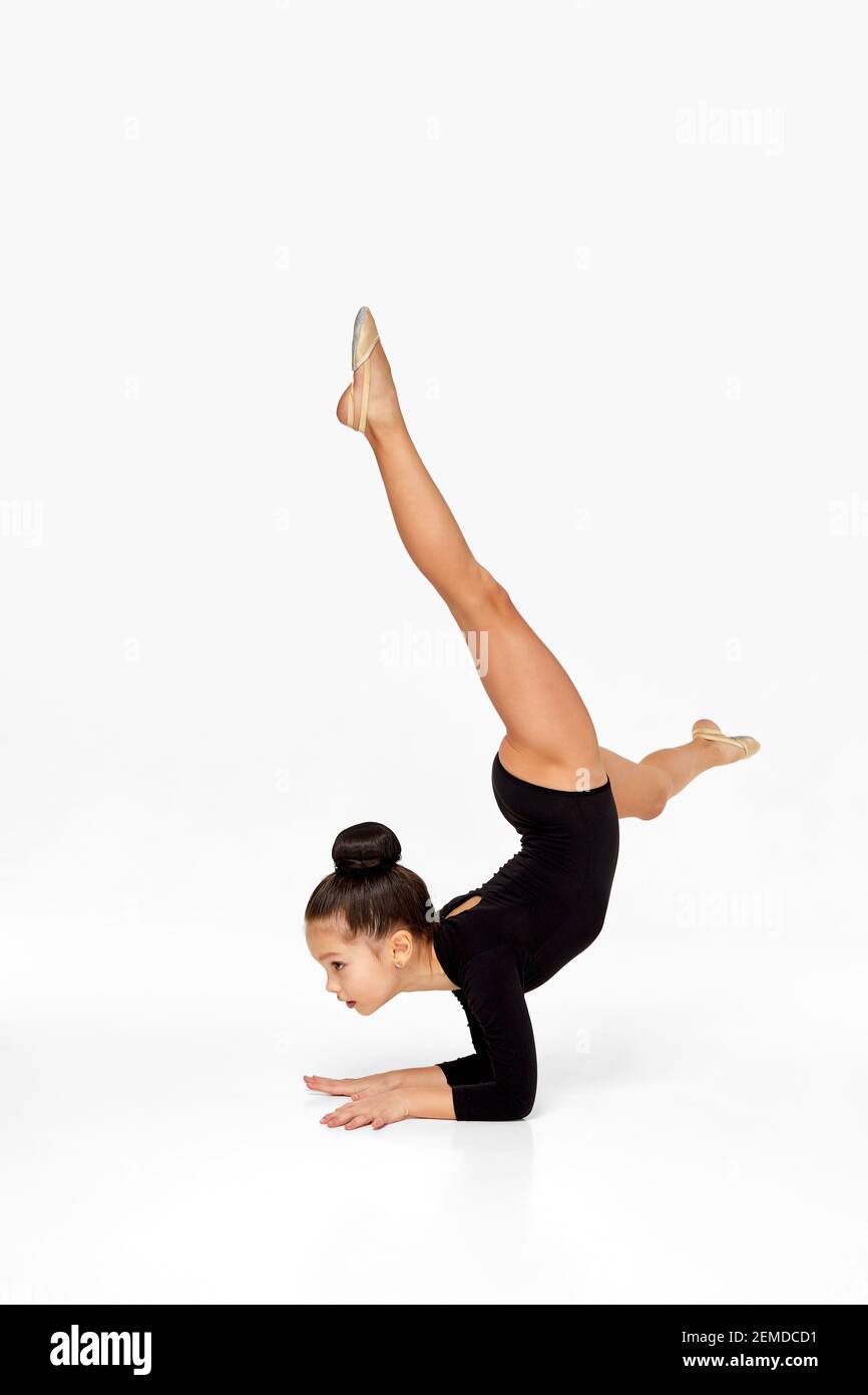 adorable little gymnast child girl in black sportswear performs a handstand. Stock Photo