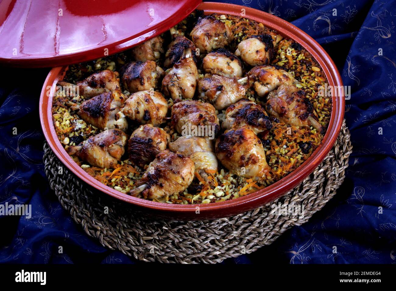 Traditional Tajine Berber Dish Made with Chicken Legs, couscous or rice, blue fabric background Stock Photo