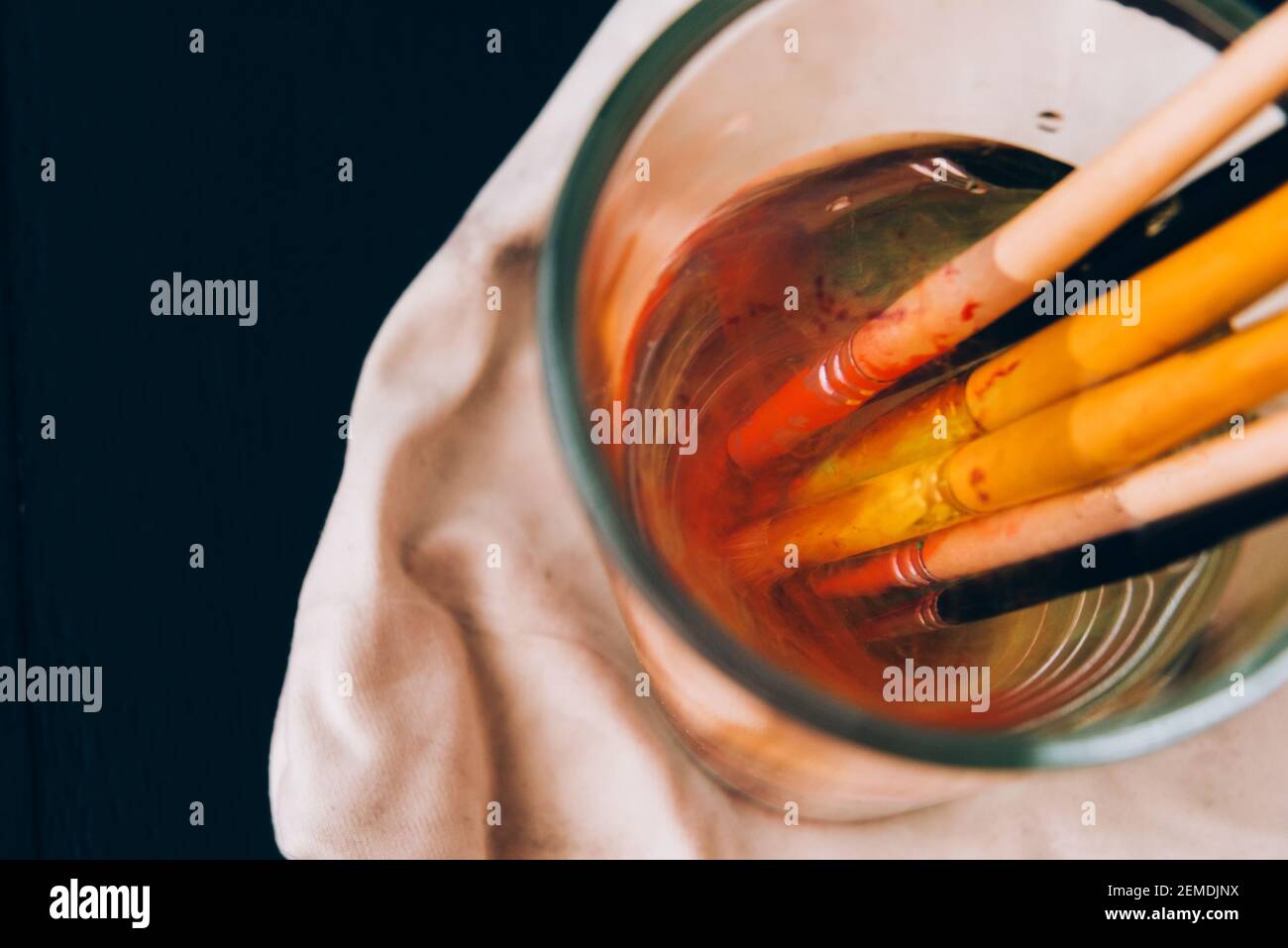 Artistic brushes soiled in paint soak in a glass with water Stock Photo