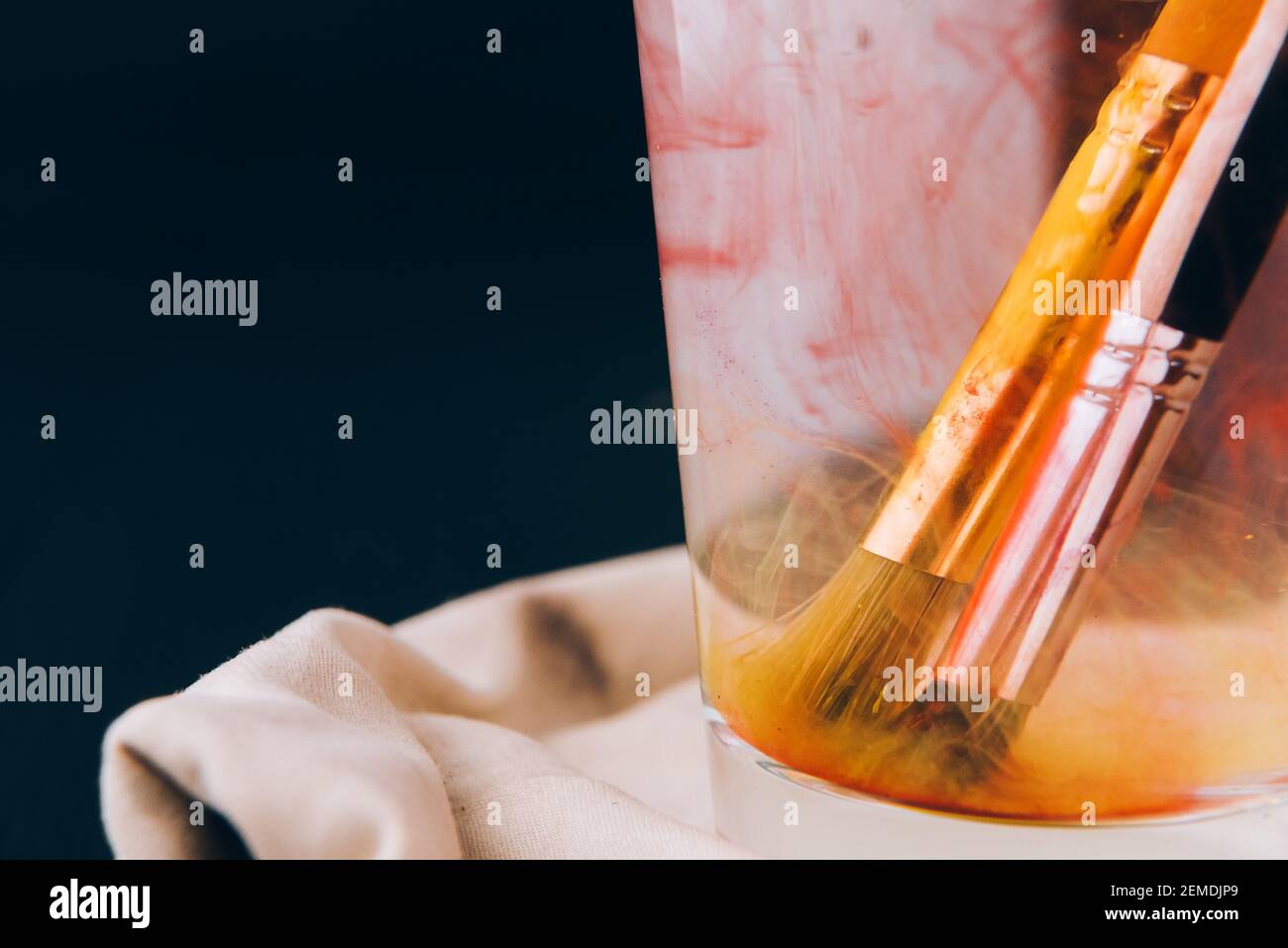 Artistic brushes soiled in paint soak in a glass with water Stock Photo