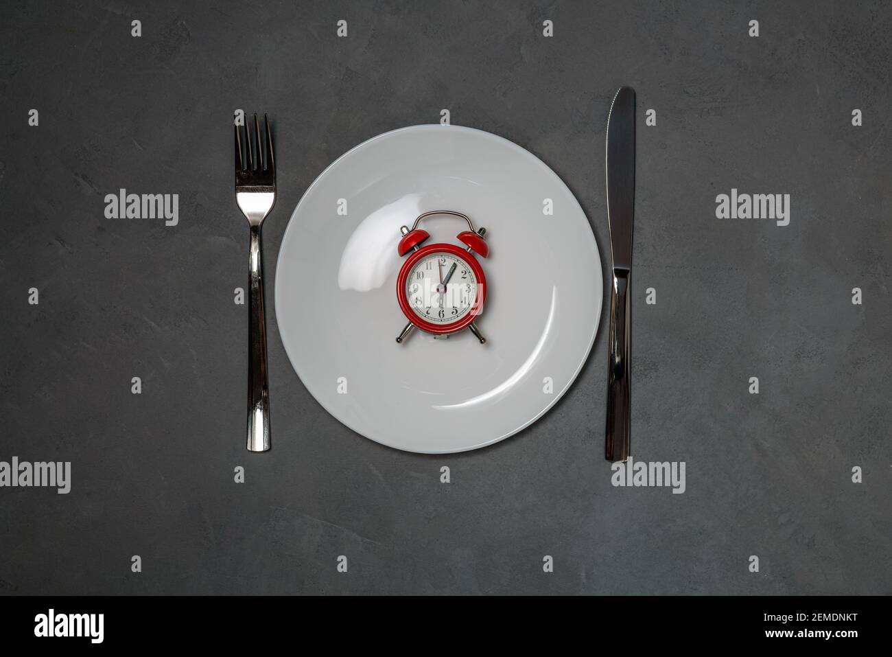 Plate with red alarm clock. intermittent fasting diet concept Stock Photo