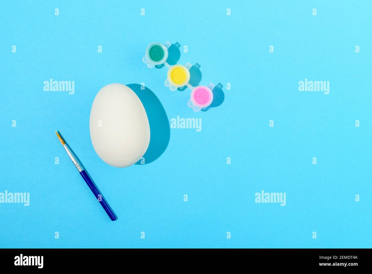 Easter egg painting set. Brush and paint on light blue background Stock