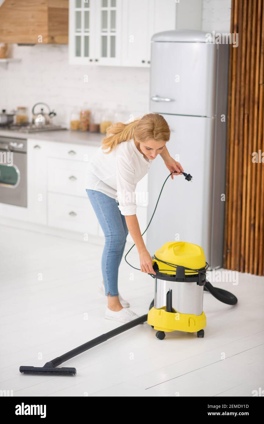 Woman about to vacuum floor of house Stock Photo