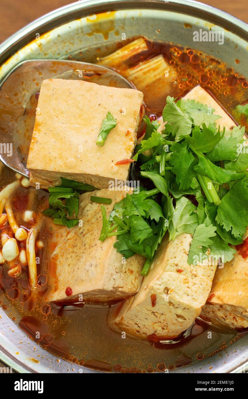 Eating stinky tofu hot pot with spicy soup using spoon, traditional