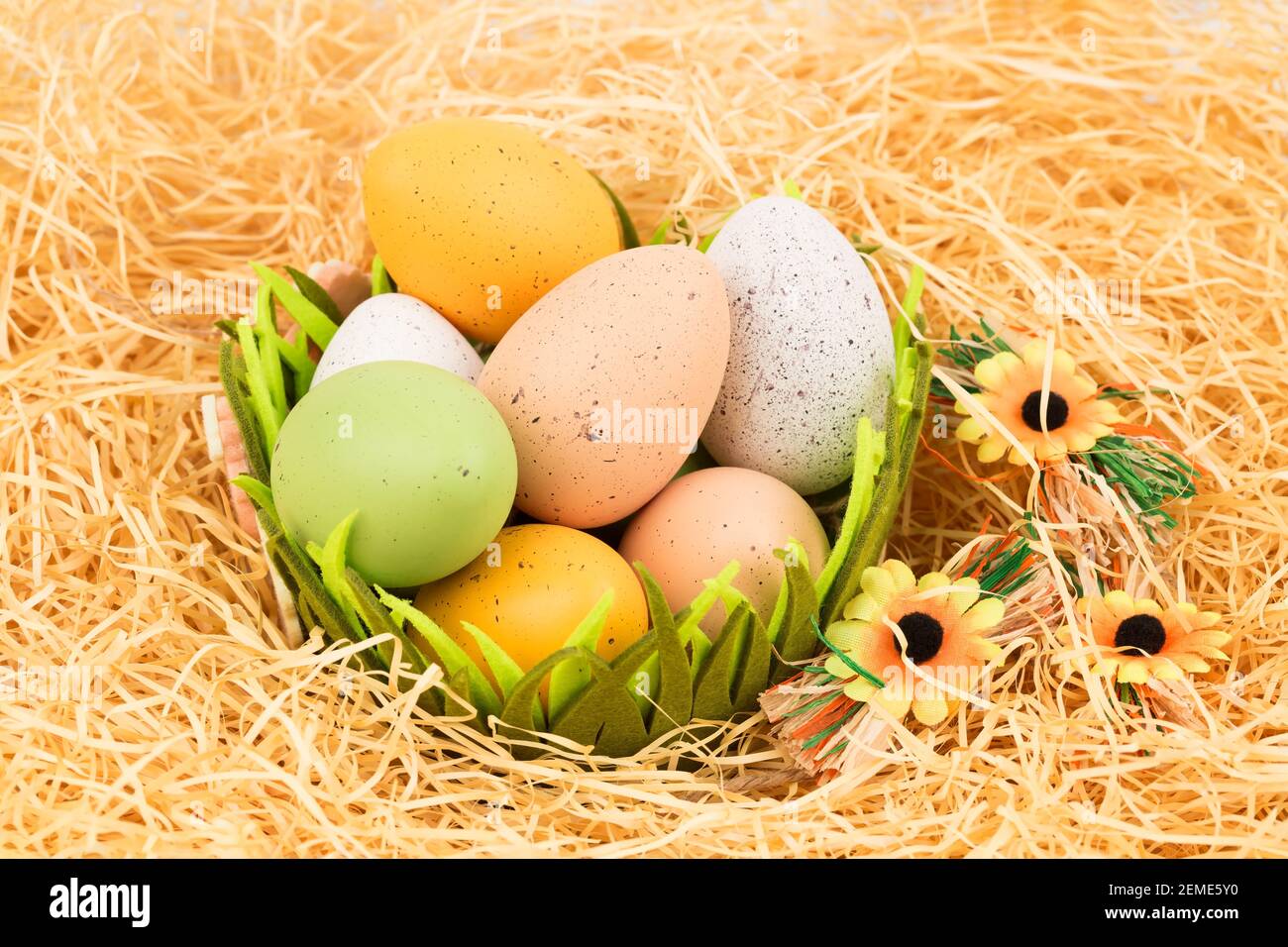Easter colorful eggs in basket and flowers on straw background Stock ...