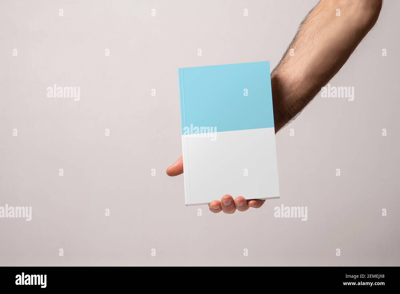 Male hand holding a closed bookcatalog with blank cover, editable mock