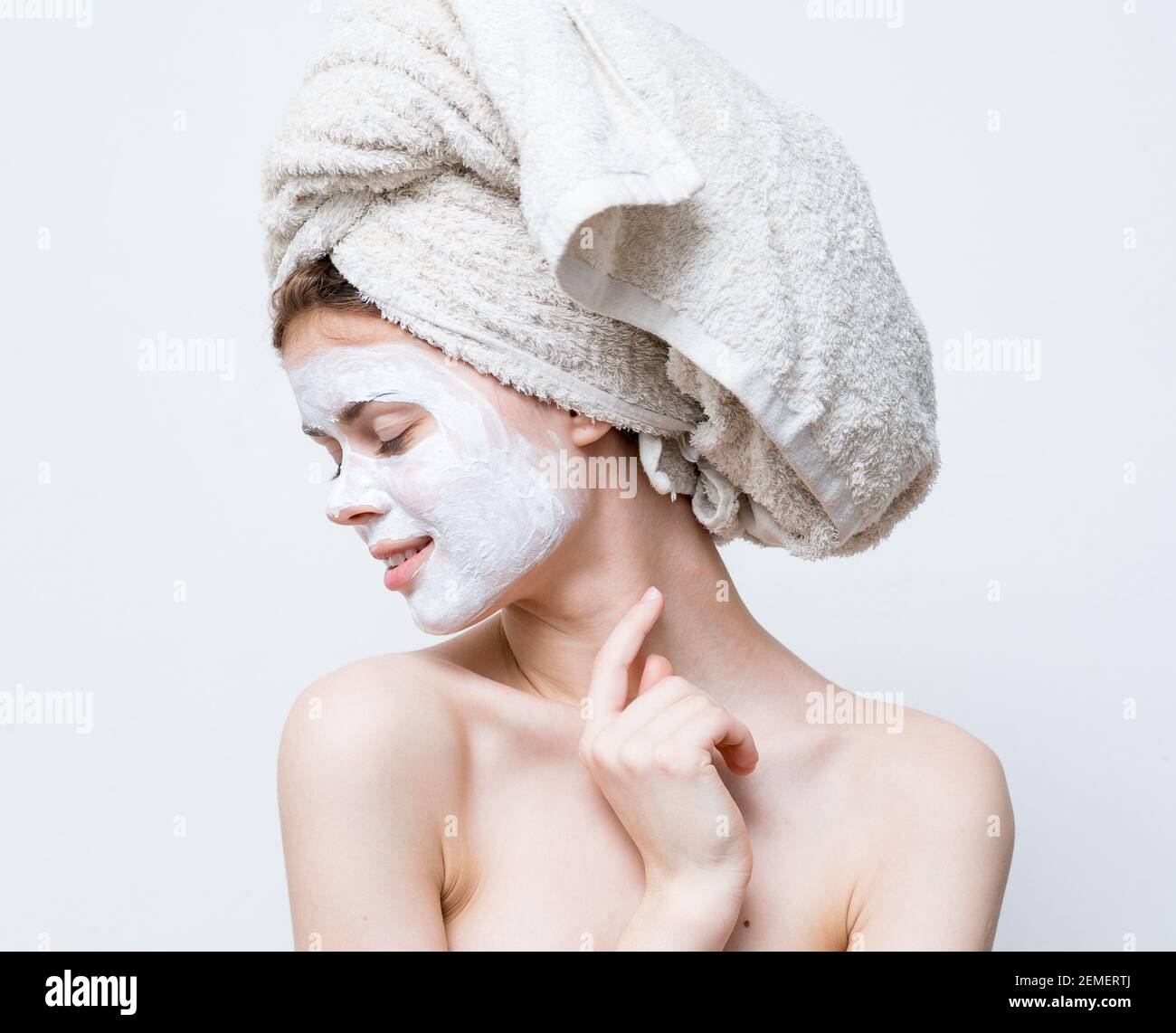 pretty woman with a towel on her head and a white mask against black ...