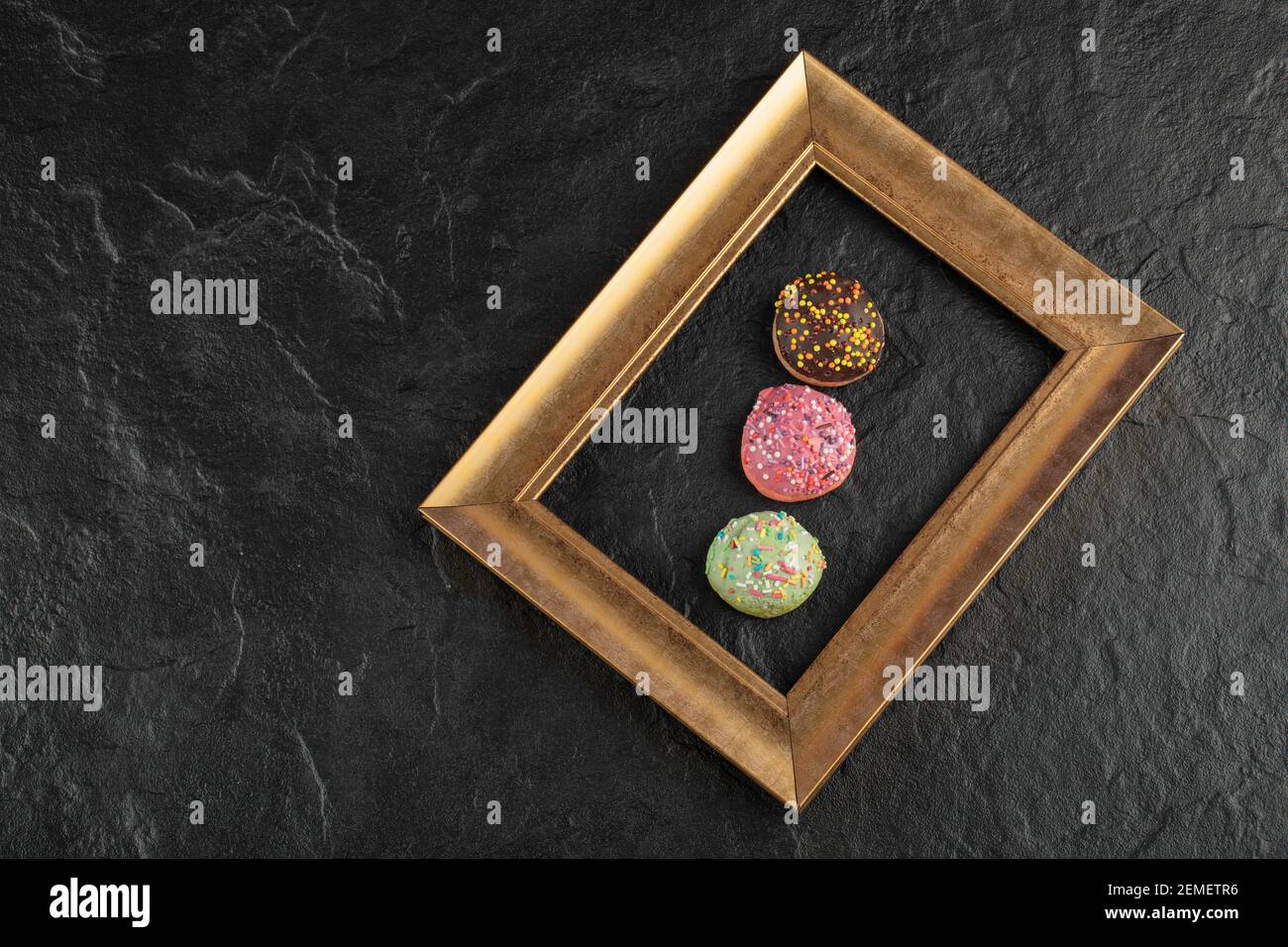 Sweet small doughnuts with sprinkles on a black background Stock Photo