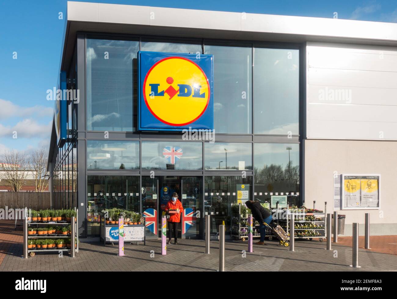 Mature woman wearing facemask leaving Lidl store front, Washington, north east England, UK Stock Photo