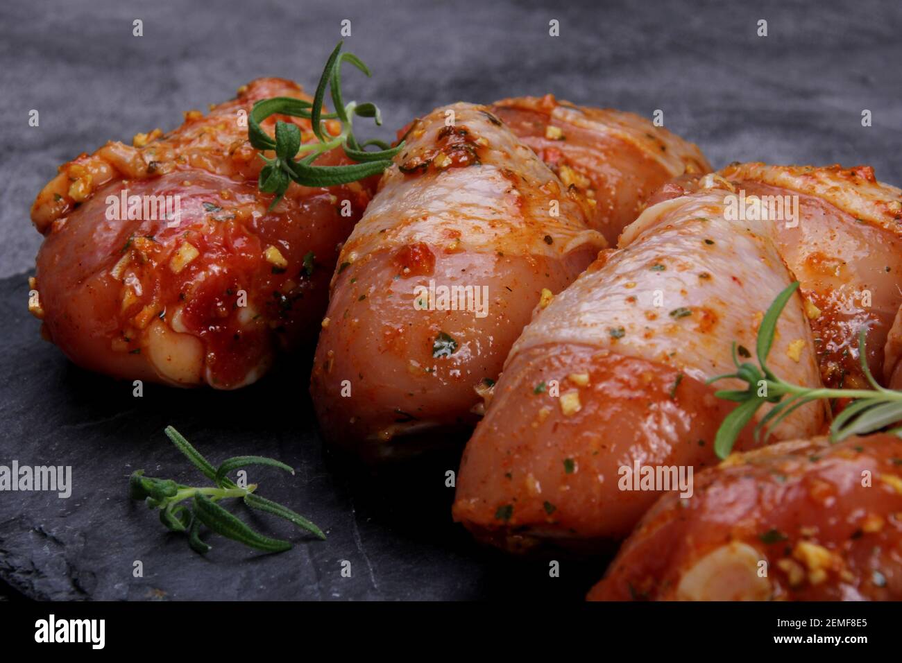 Marinated raw chicken legs on black pan. Uncooked marinated chicken