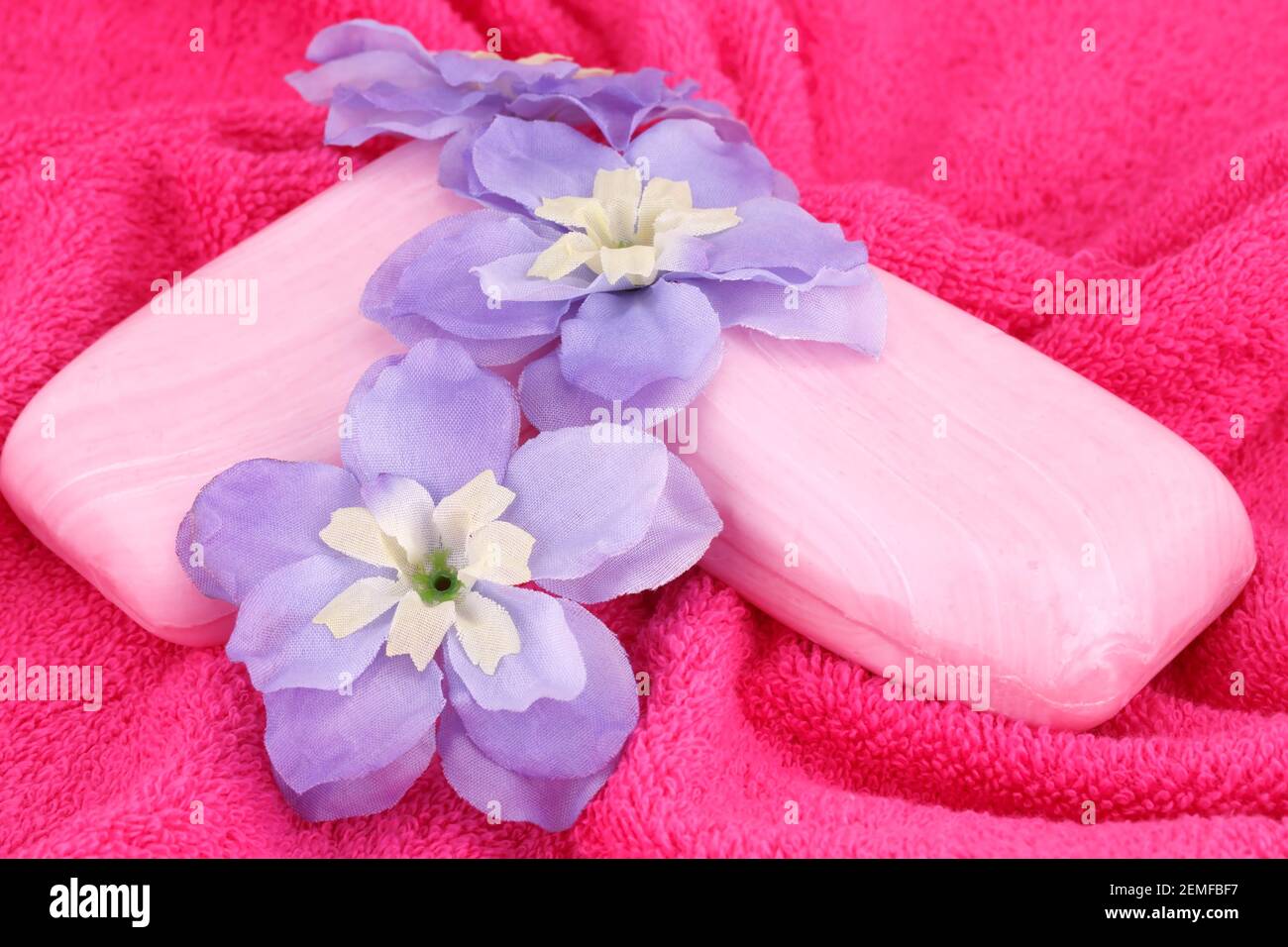 Pink soaps and flowers on red towel. Stock Photo