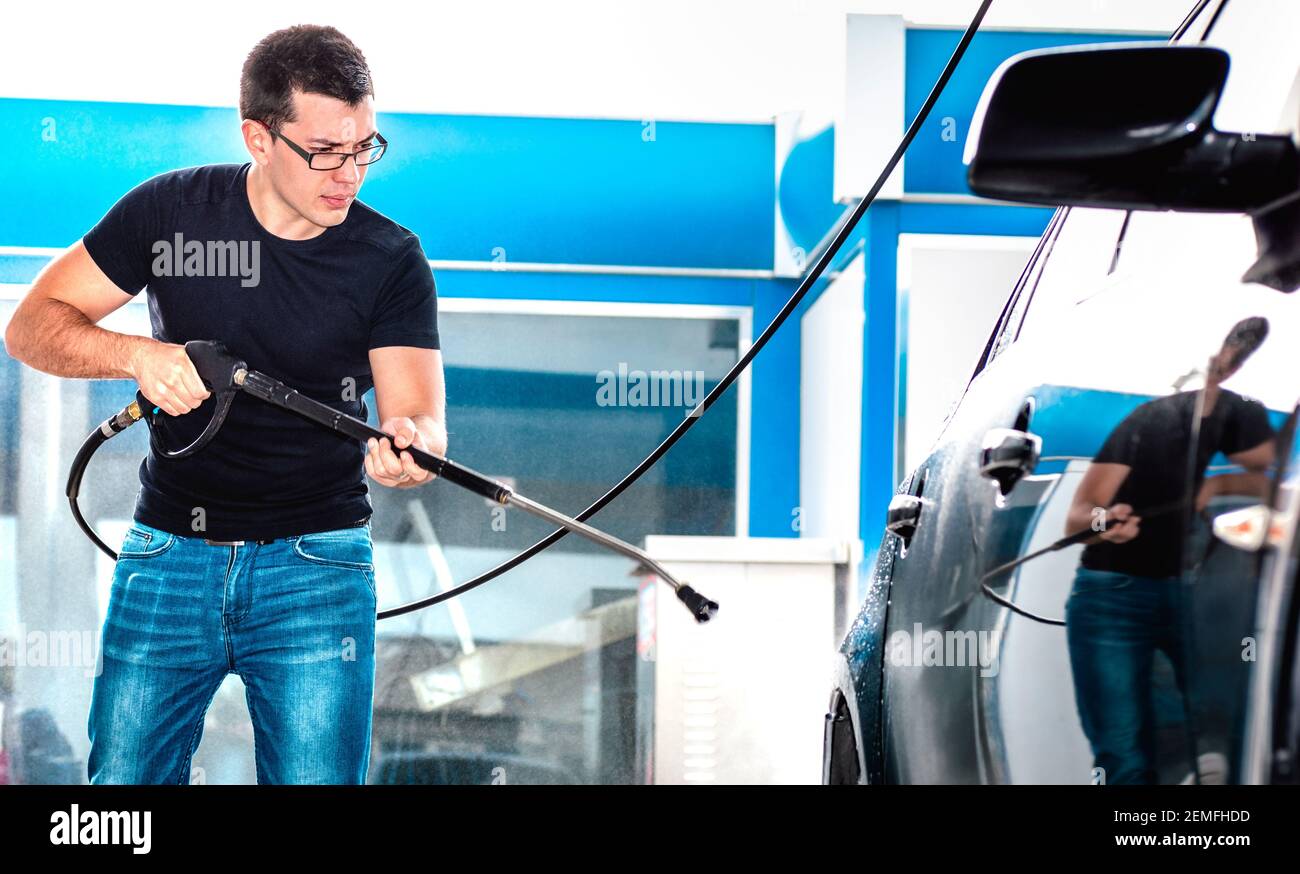 Professional carwash employee washing car at wash station Working