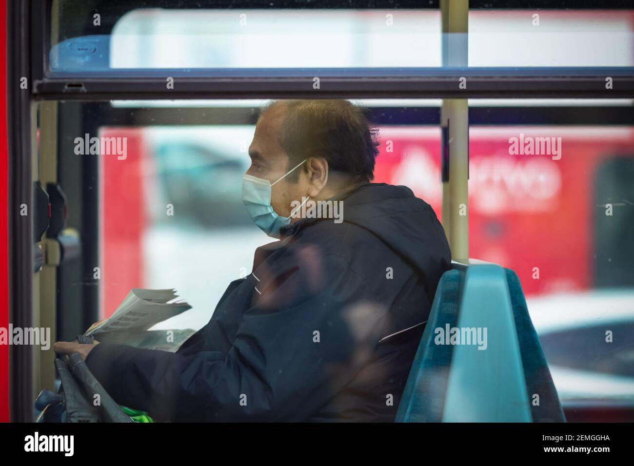 London, UK - 5 February, 2021 - A British Asian man with a protective face mask on a double-decker bus Stock Photo